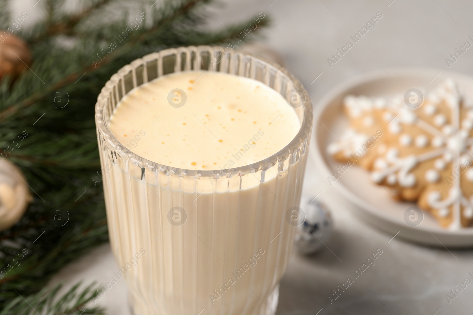 Photo of Glass of delicious eggnog on light table, closeup