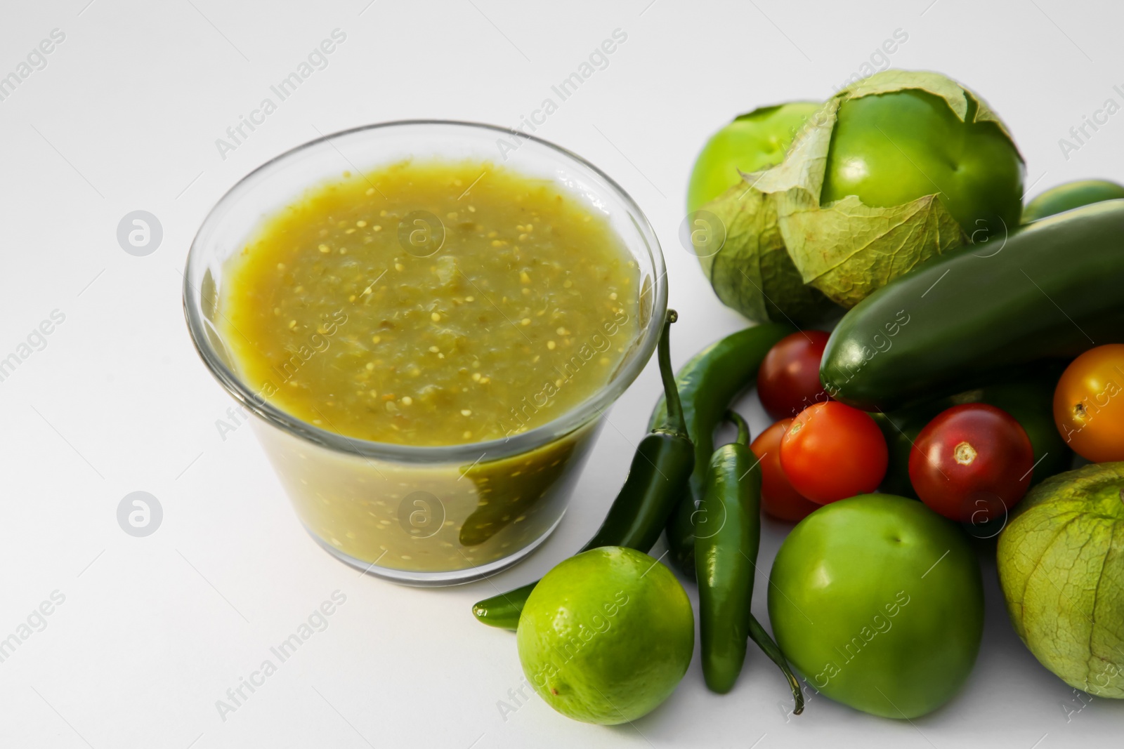 Photo of Bowl with delicious salsa sauce and ingredients on white background, closeup