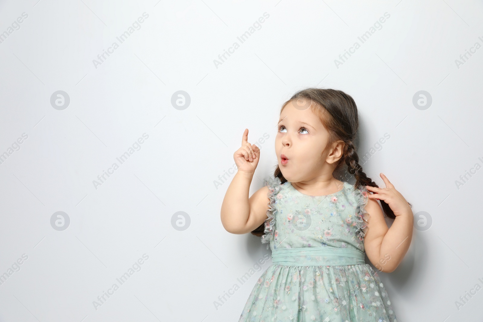 Photo of Cute little girl on light grey background. Space for text