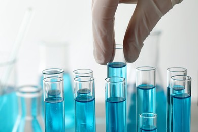 Photo of Scientist taking test tube with light blue liquid in laboratory, closeup