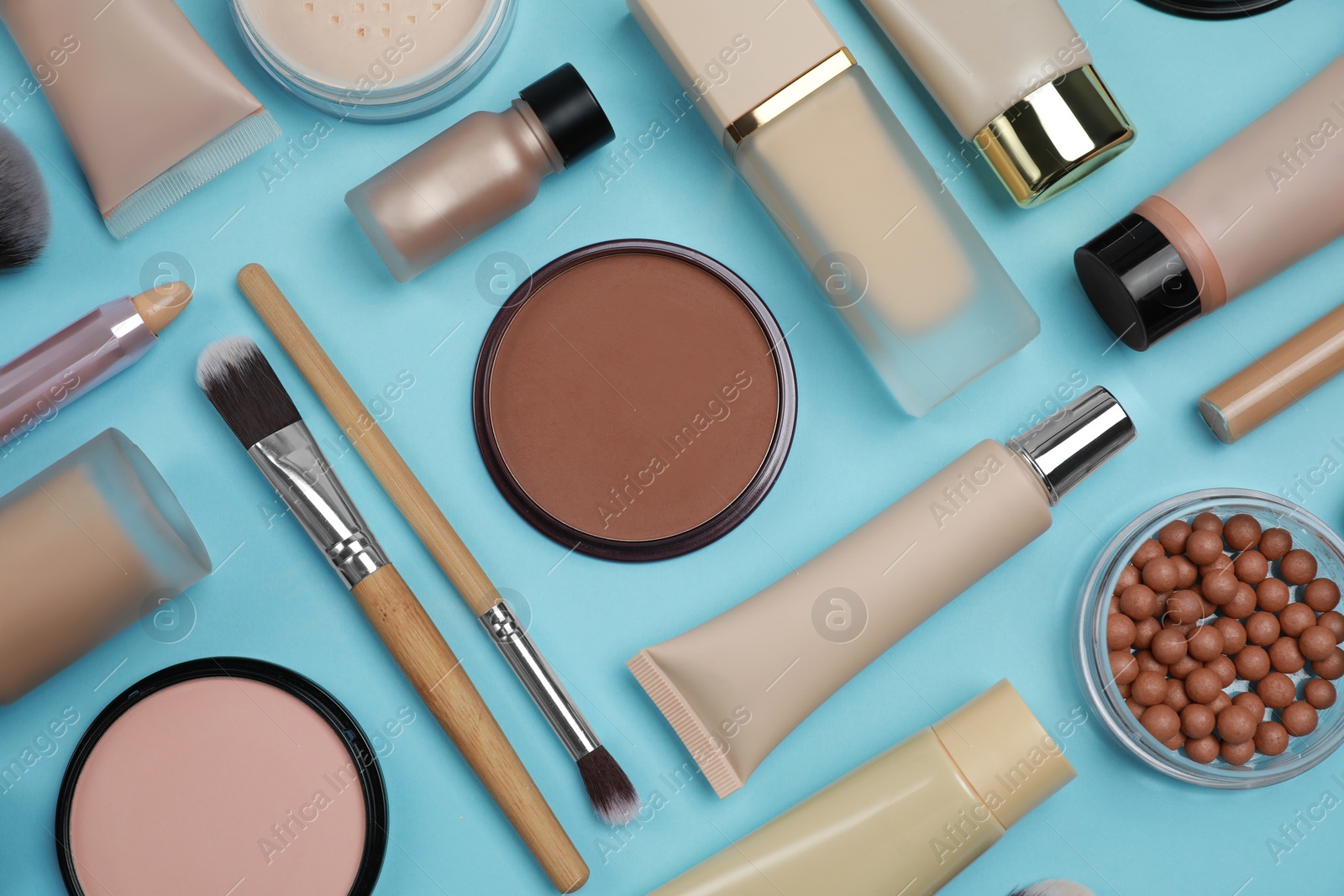 Photo of Face powders and other decorative cosmetic products on light blue background, flat lay