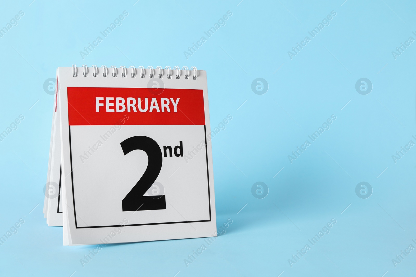 Photo of Calendar with date February 2nd on light blue background, space for text. Groundhog day