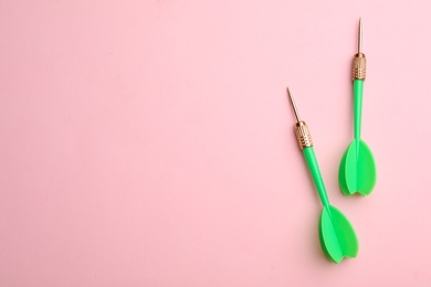 Photo of Green dart arrows on pink background, flat lay with space for text