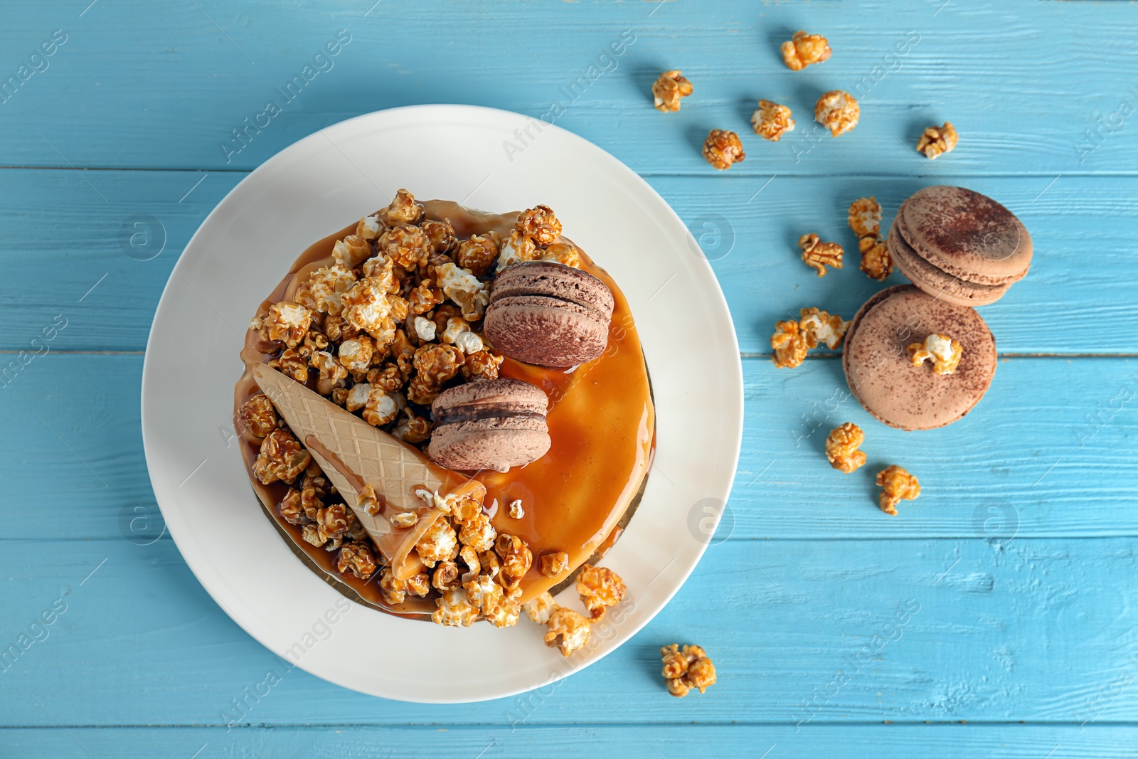 Photo of Delicious homemade cake with caramel sauce and popcorn on table, top view