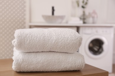 Photo of Clean folded towels on wooden table in laundry room