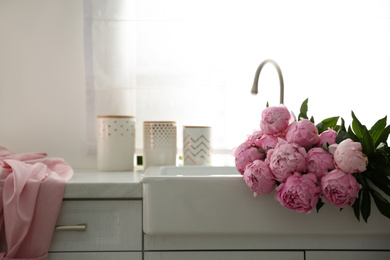 Bouquet of beautiful pink peonies in kitchen sink