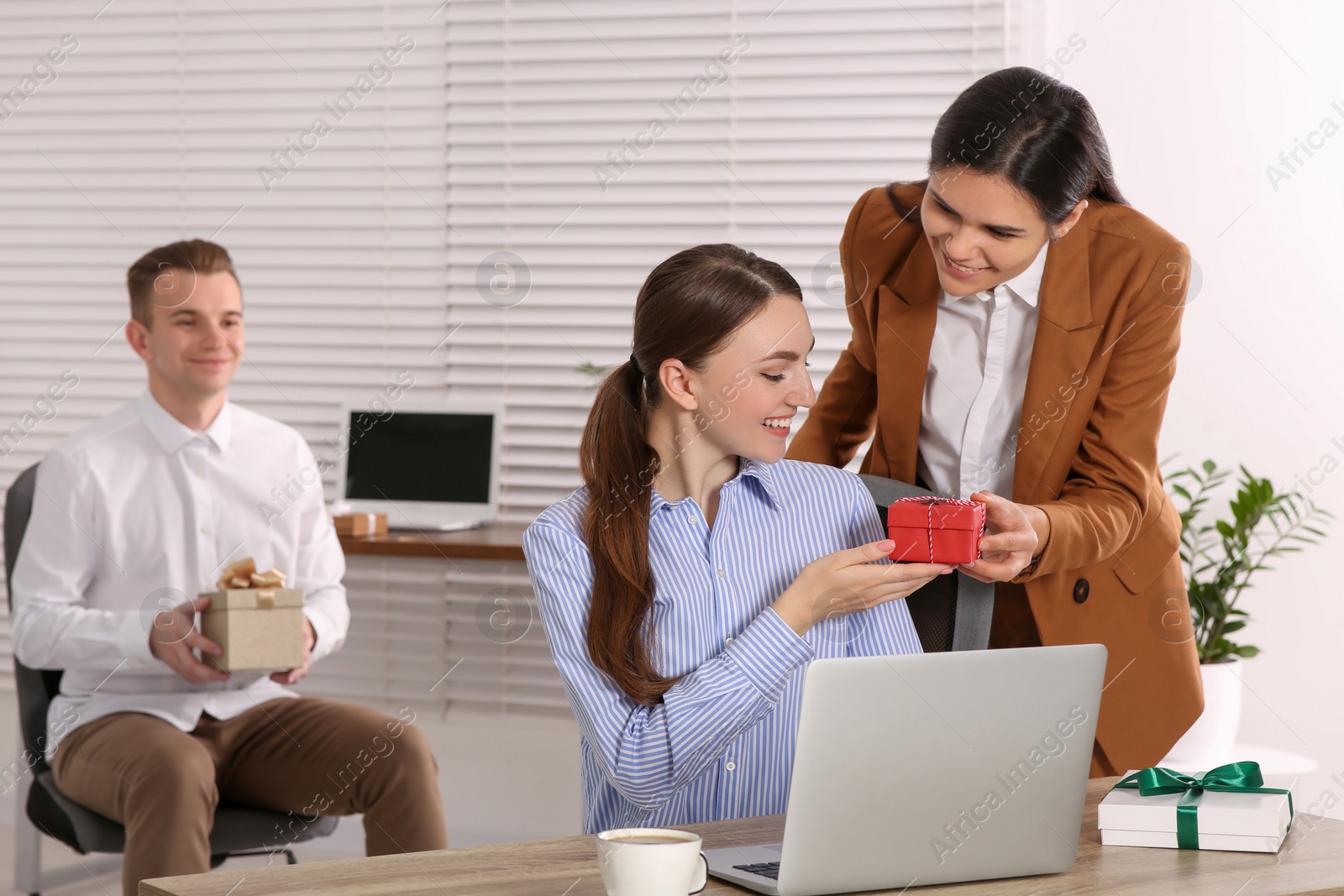 Photo of Woman presenting gift to her colleague in office