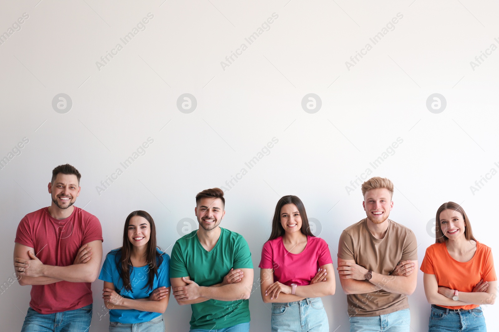 Photo of Group of happy people posing near light wall