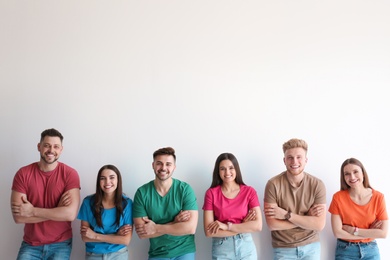 Group of happy people posing near light wall