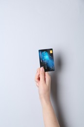 Woman holding credit card on light grey background, closeup