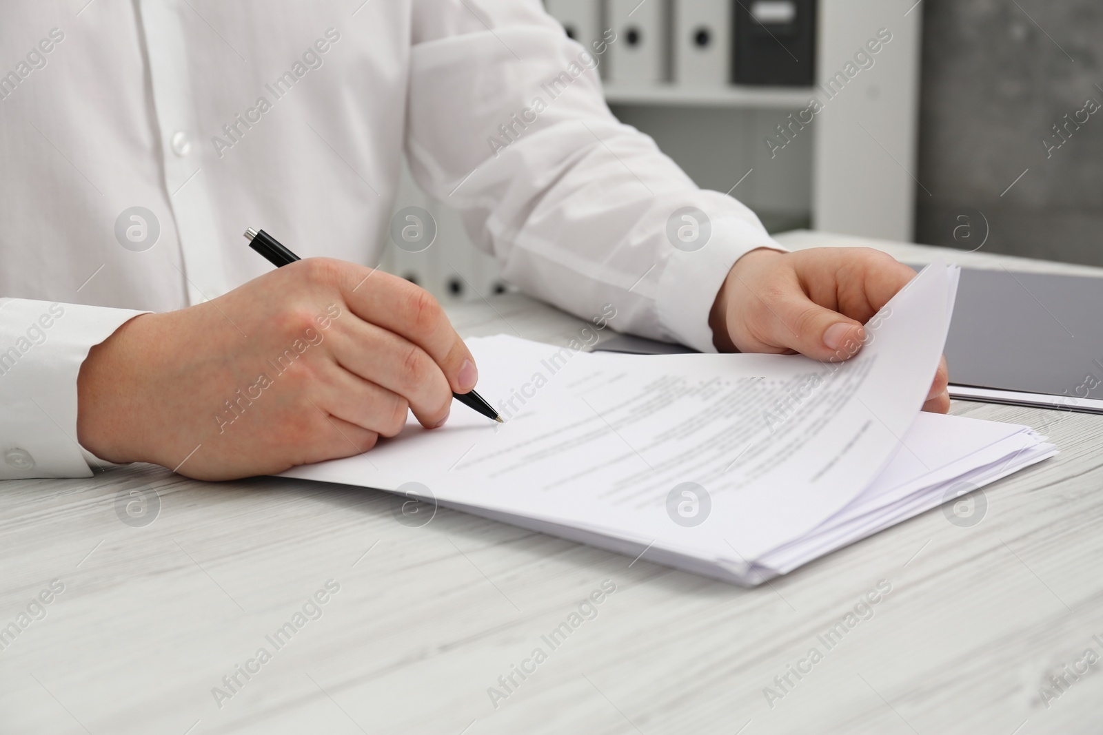 Photo of Man signing document at wooden table, closeup