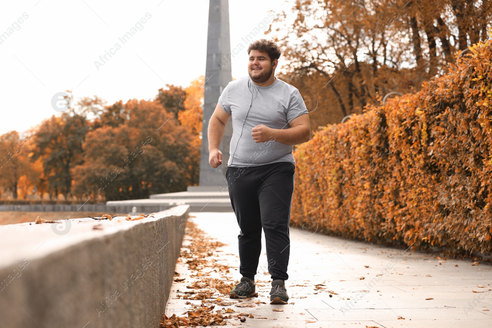 Photo of Young overweight man running in park. Fitness lifestyle