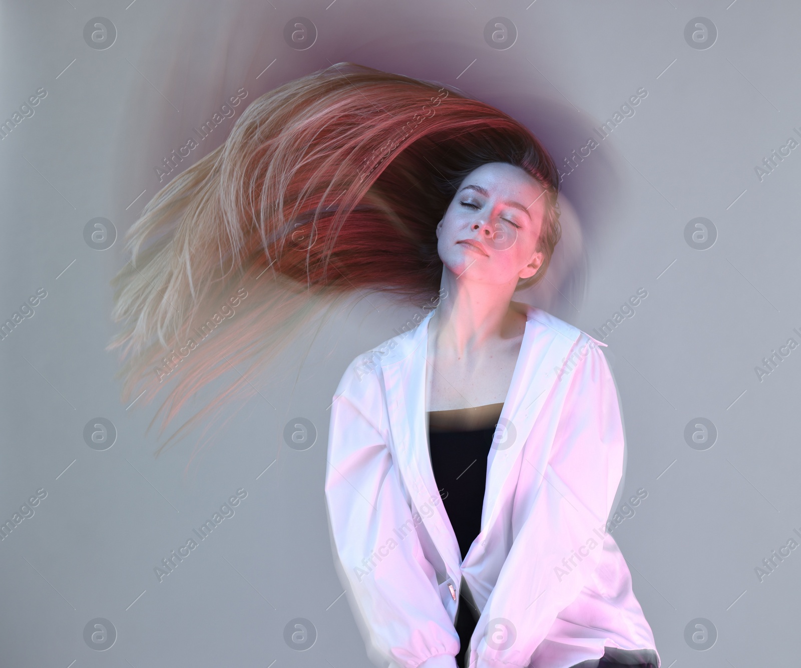 Photo of Fashionable portrait of beautiful young woman on grey background, long-exposure photography