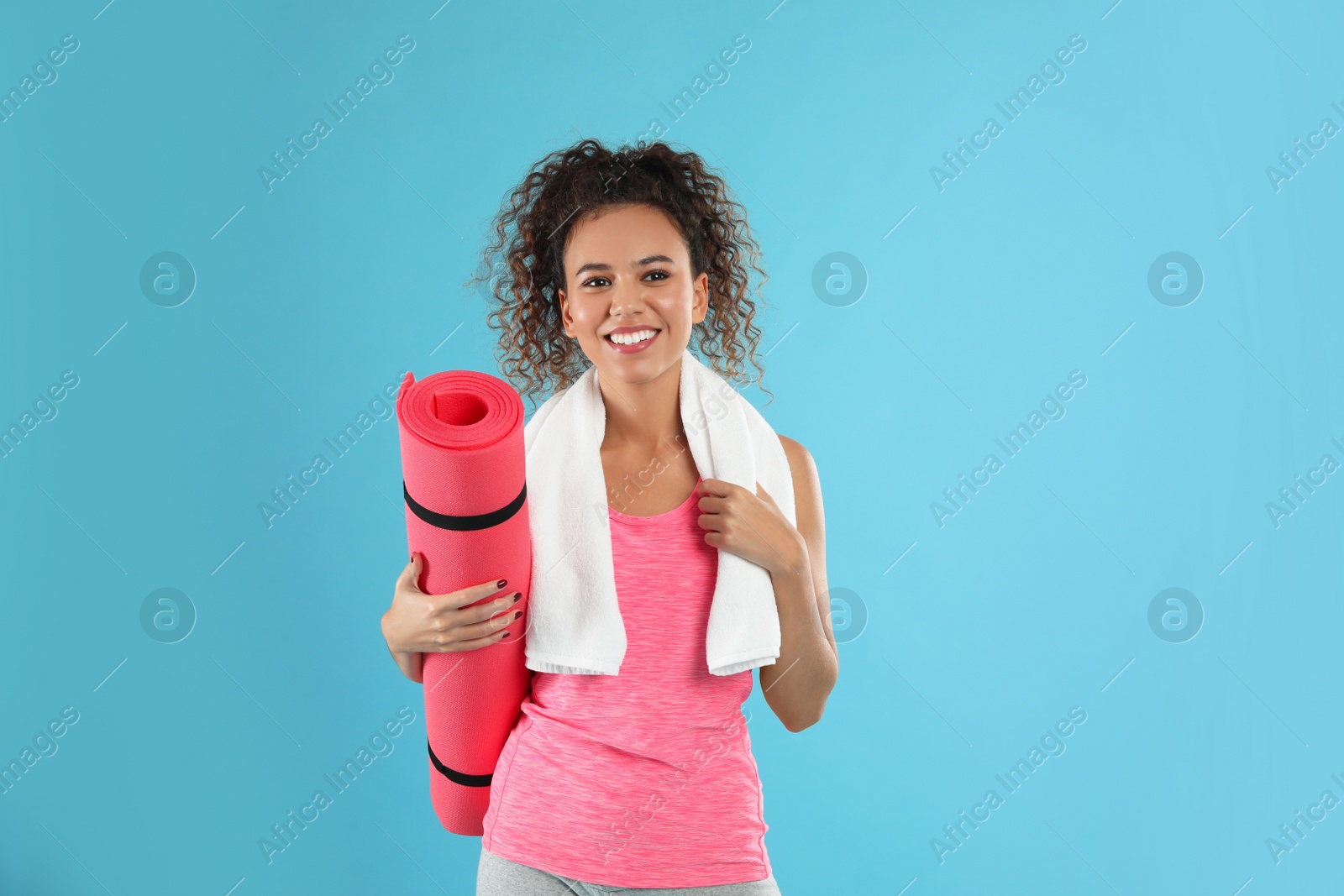 Photo of Beautiful African American woman with yoga mat and towel on turquoise background