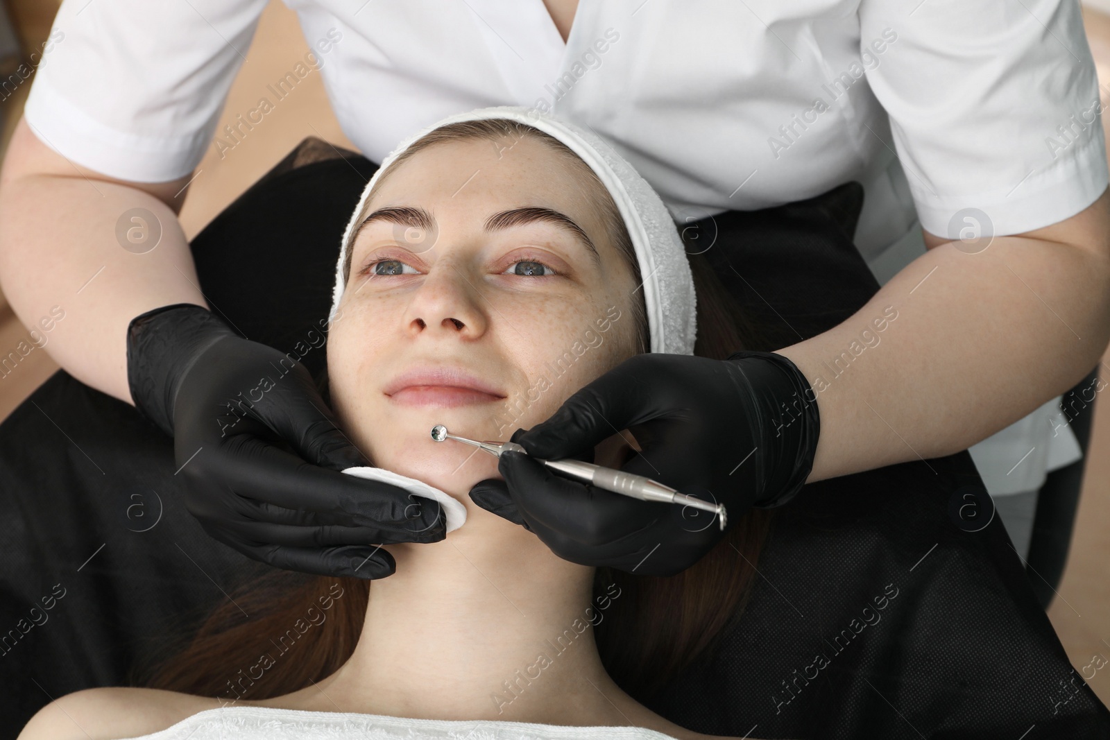 Photo of Cosmetologist using scrubber, closeup. Client having cleansing procedure