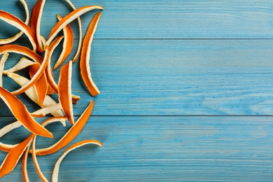 Photo of Dry orange peels on light blue table, flat lay. Space for text