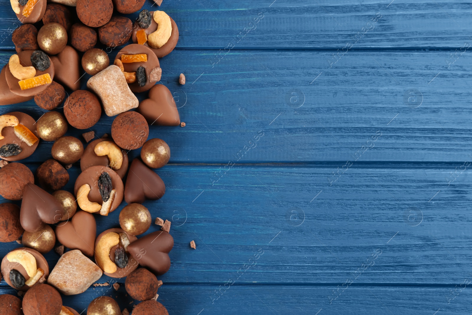 Photo of Different delicious chocolate candies on blue wooden table, flat lay. Space for text