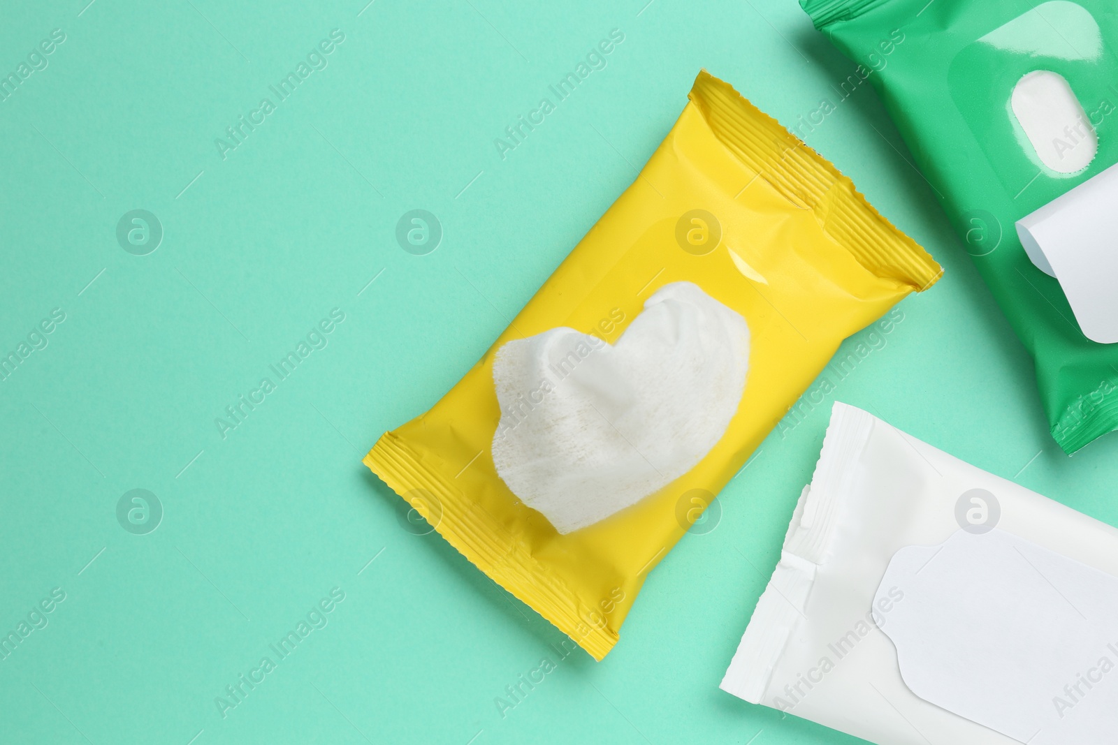 Photo of Wet wipes flow packs on turquoise background, flat lay. Space for text