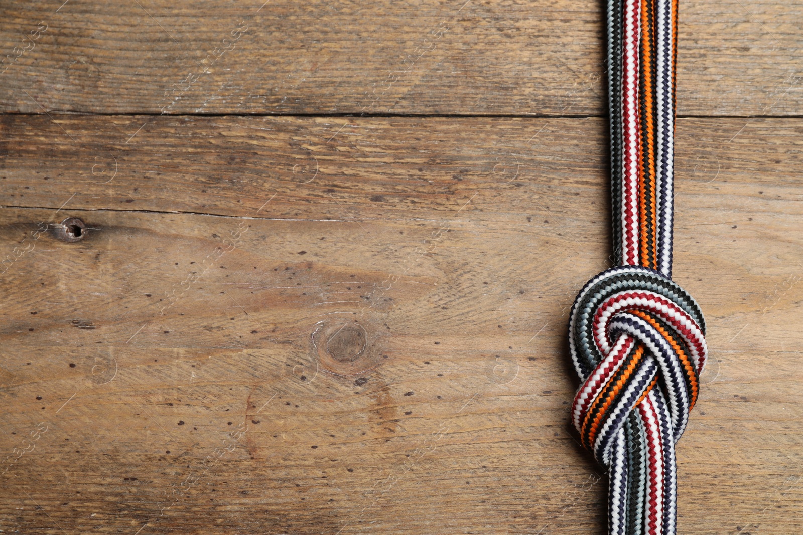 Photo of Top view of colorful ropes tied together on wooden background, space for text. Unity concept