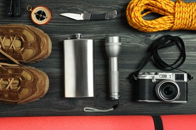 Photo of Flat lay composition with different camping equipment on dark wooden background. Traveler set
