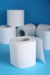 Photo of Soft toilet paper rolls on light blue background