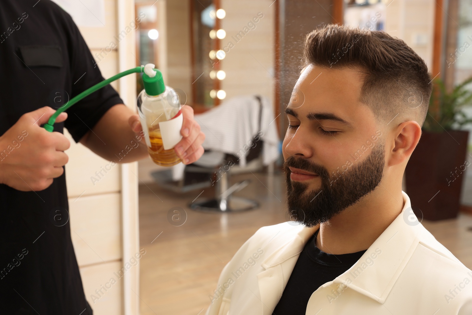 Photo of Professional hairdresser working with client in barbershop, closeup