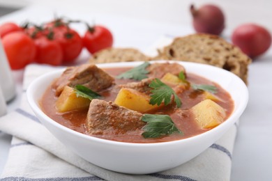 Photo of Delicious goulash in bowl on white table, closeup