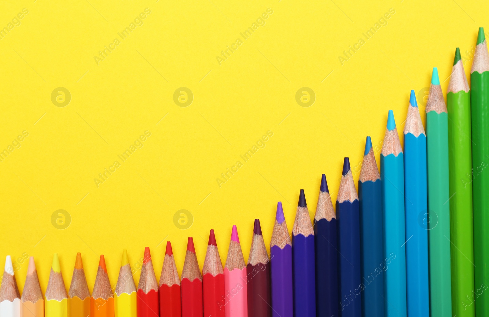 Photo of Color pencils on yellow background, flat lay. Space for text