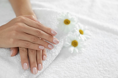 Photo of Closeup of woman with smooth hands and flowers on towel, space for text. Spa treatment