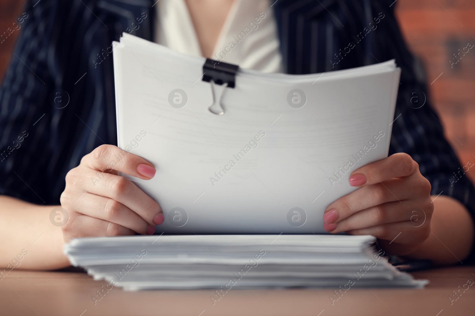 Photo of Woman stacking documents at wooden table in office, closeup
