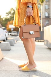 Young woman with stylish brown bag on city street, closeup