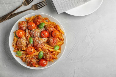 Photo of Delicious pasta with meatballs and tomato sauce on grey background