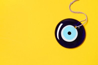 Photo of Evil eye amulet on orange background, top view. Space for text