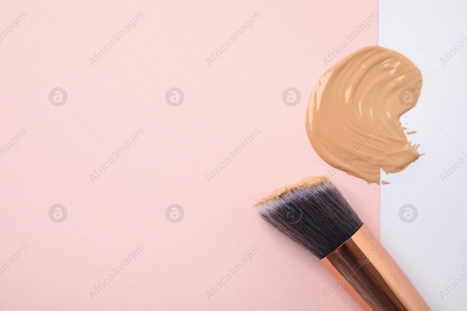 Photo of Sample of liquid foundation and makeup brush on color background, top view. Space for text