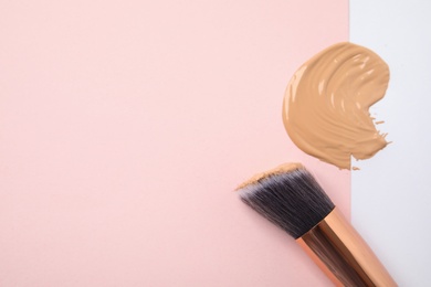 Sample of liquid foundation and makeup brush on color background, top view. Space for text