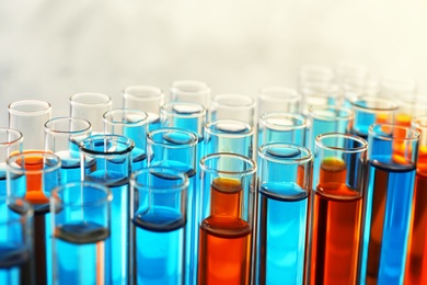 Many test tubes with different liquid samples on color background, closeup