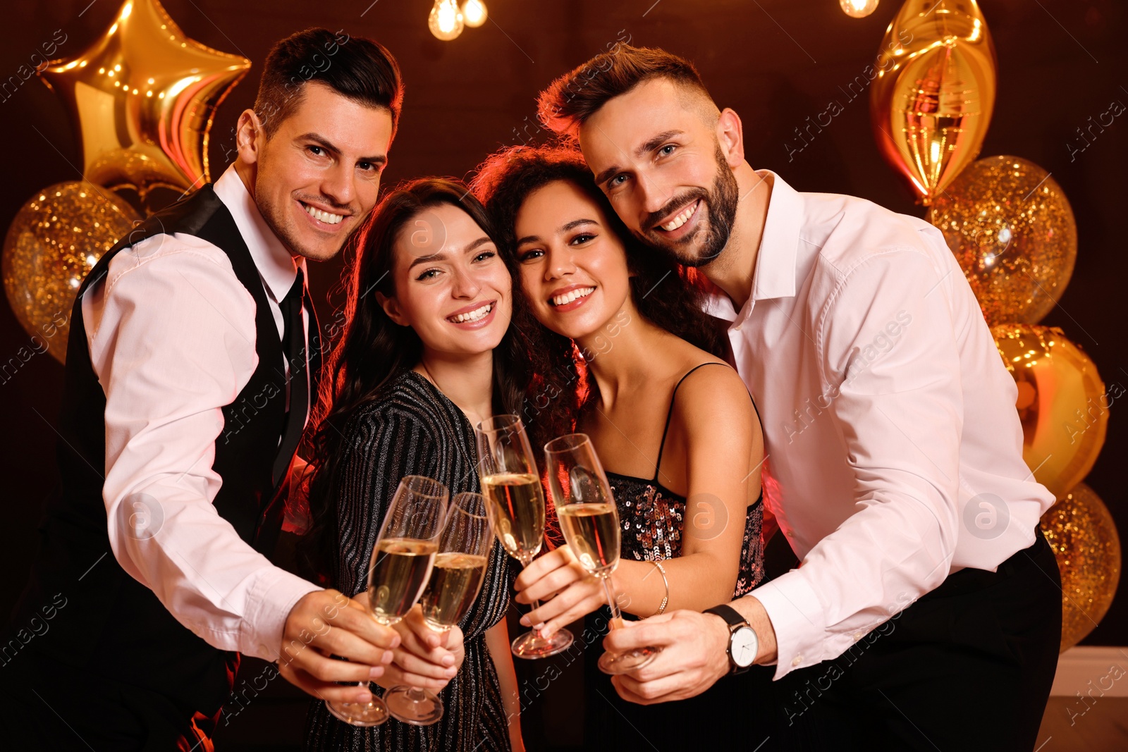 Photo of Happy friends with glasses of sparkling wine celebrating New Year indoors