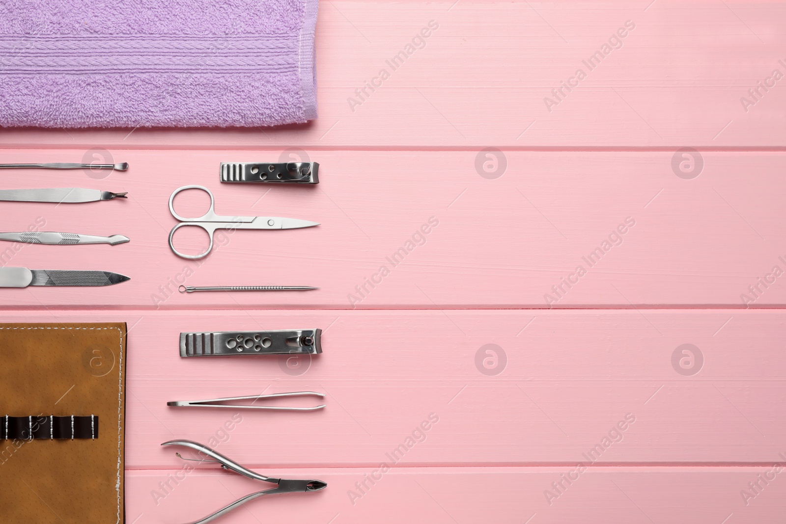 Photo of Set of manicure tools, towel and case on pink wooden background, flat lay. Space for text