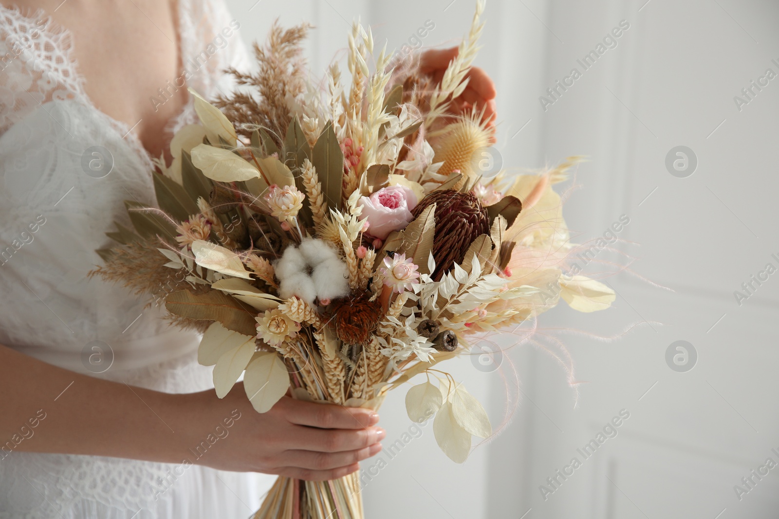 Photo of Bride holding beautiful dried flower bouquet at home, closeup