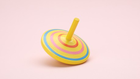 Photo of One bright spinning top on beige background. Toy whirligig