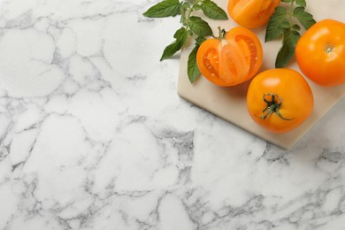 Fresh ripe yellow tomatoes on white marble table, top view. Space for text