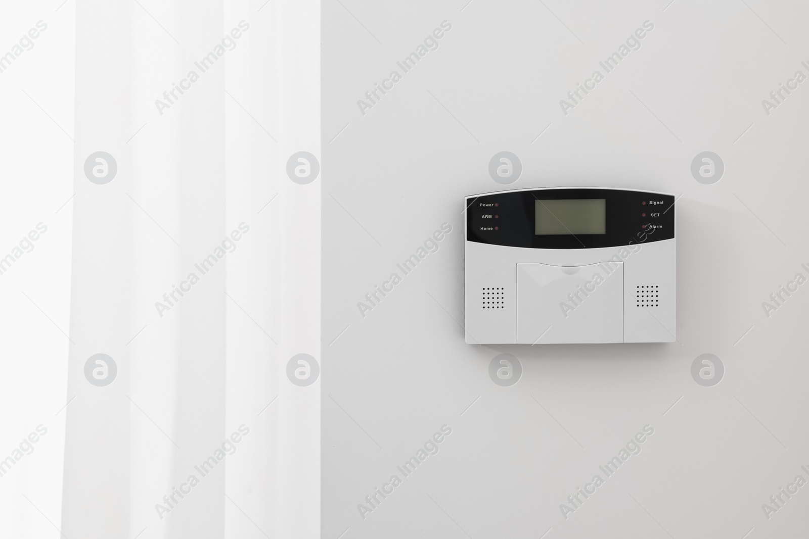 Photo of Home security alarm system on white wall indoors, space for text