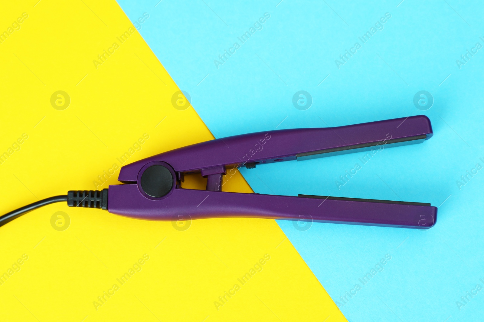 Photo of Modern hair iron for straightening on color background, top view