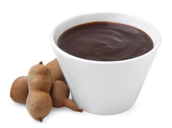Photo of Bowl of tamarind sauce and fresh pods isolated on white