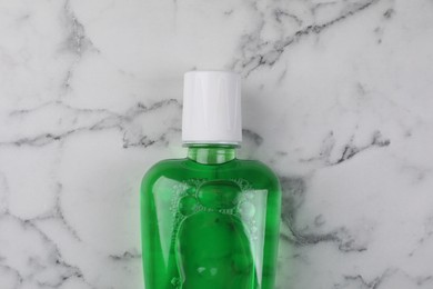 Photo of Fresh mouthwash in bottle on white marble table, top view