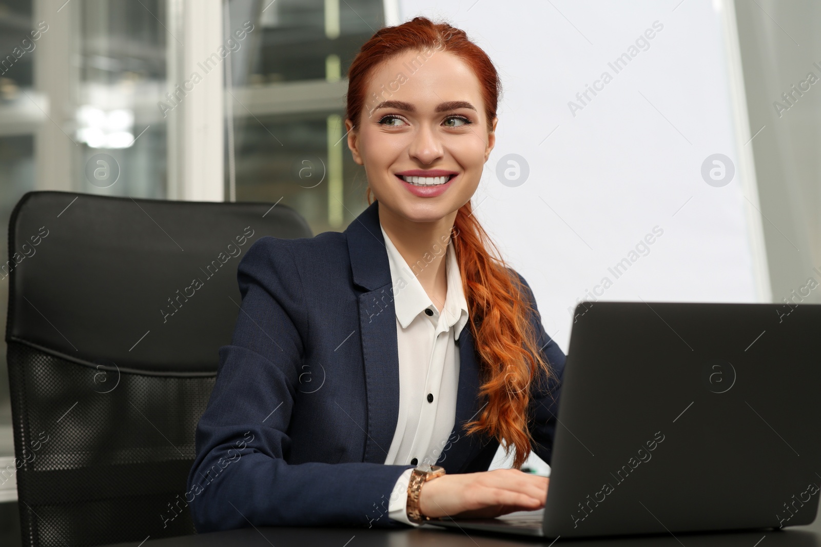 Photo of Happy woman working with laptop at black desk in office