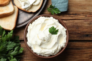 Photo of Toasted bread and delicious cream cheese with parsley on wooden table, flat lay