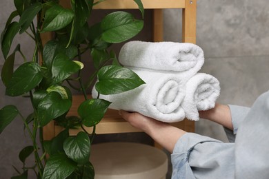 Woman putting rolled towels onto shelf indoors, closeup