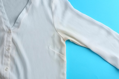 Clothes with deodorant stain on light blue background, top view