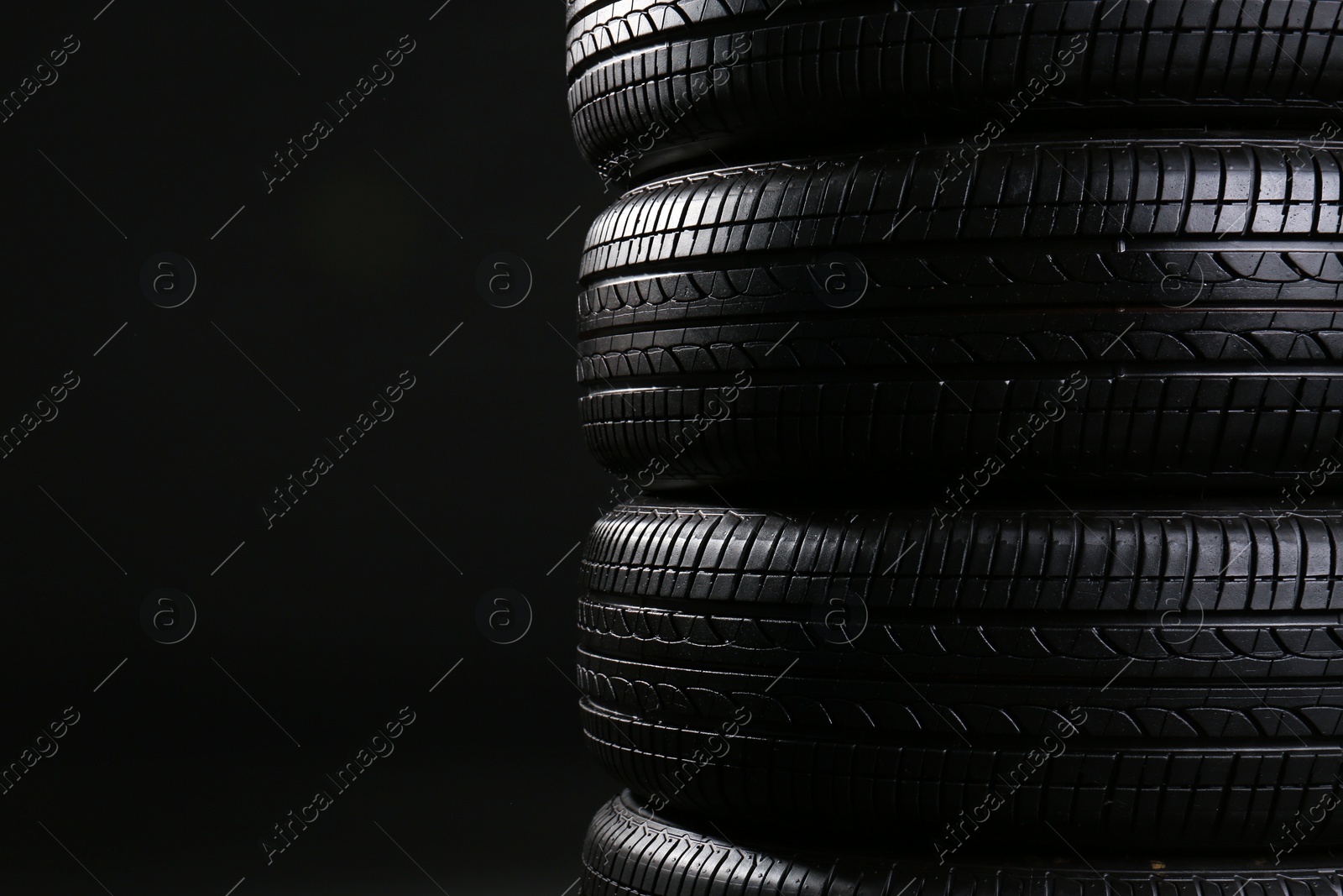 Photo of Stack of car tires on black background, closeup